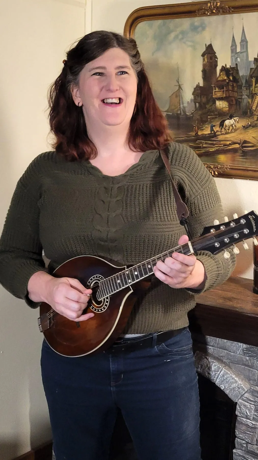 Morgan, who runs the ads and accounts, laughing while playing a mandolin at home.