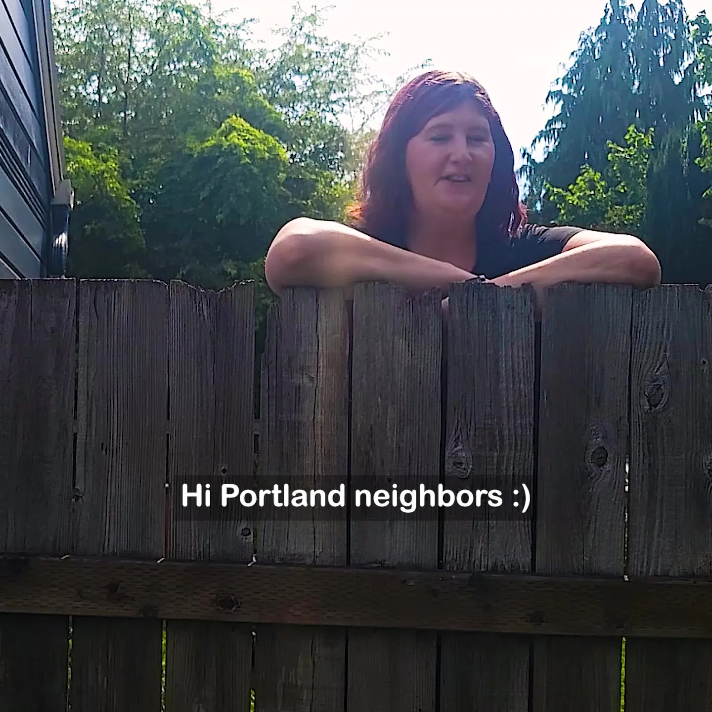 Morgan leaning over a backyard fence to greet her Portland neighbors, a still from the video ad we made for our own business.